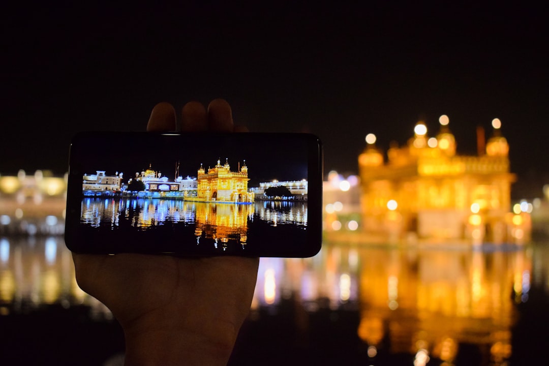 person holding smartphone taking photo of city buildings during night time